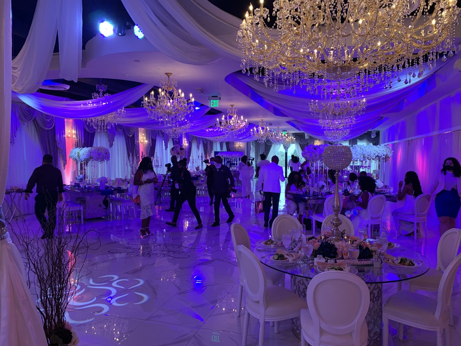 Elegant wedding reception ballroom with chandeliers and colorful uplighting